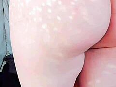 Sissy crossdresser in pink shirt and black mini skirt shows off white legs and big butt.